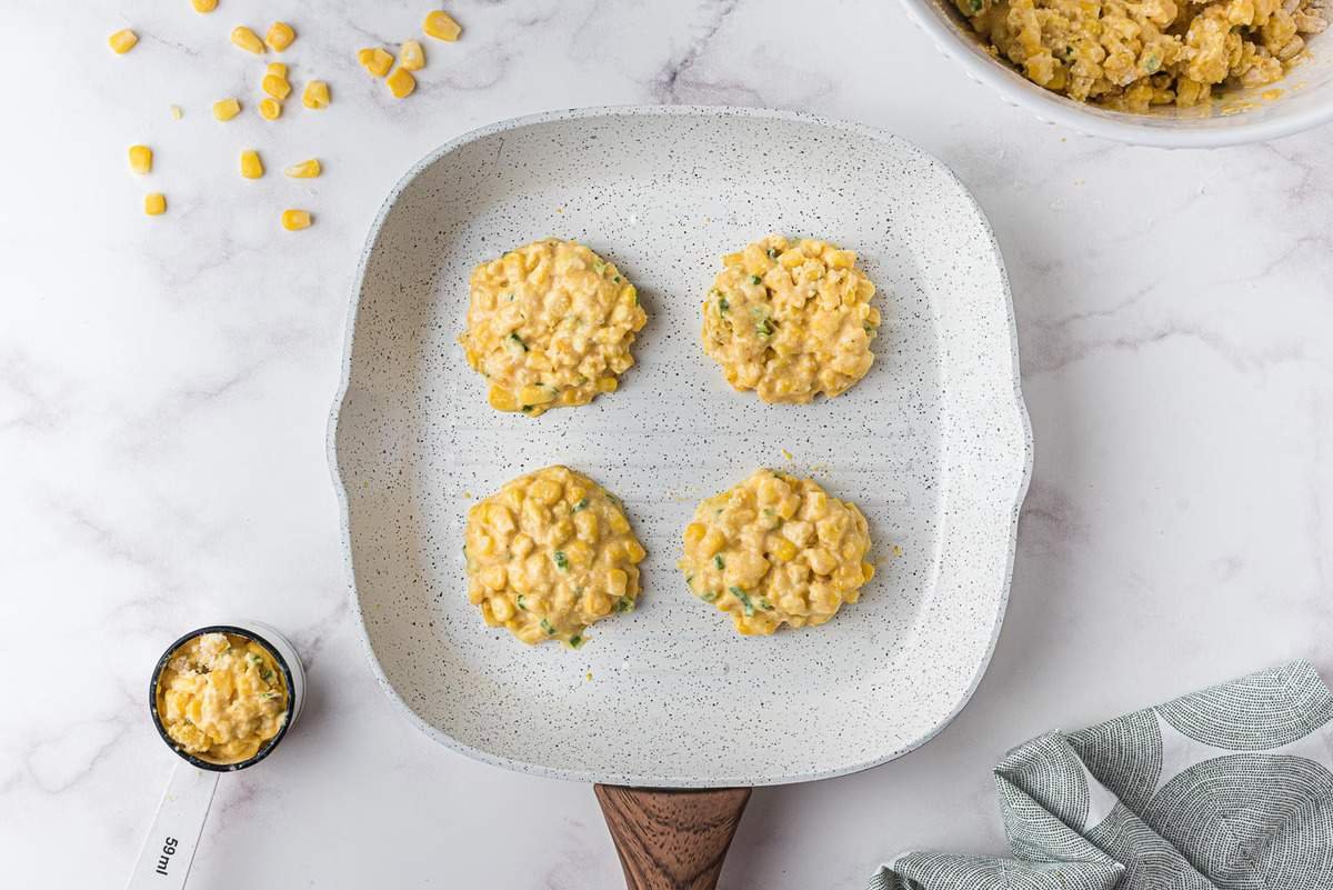 Panqueques de maíz crudos en una sartén blanca.